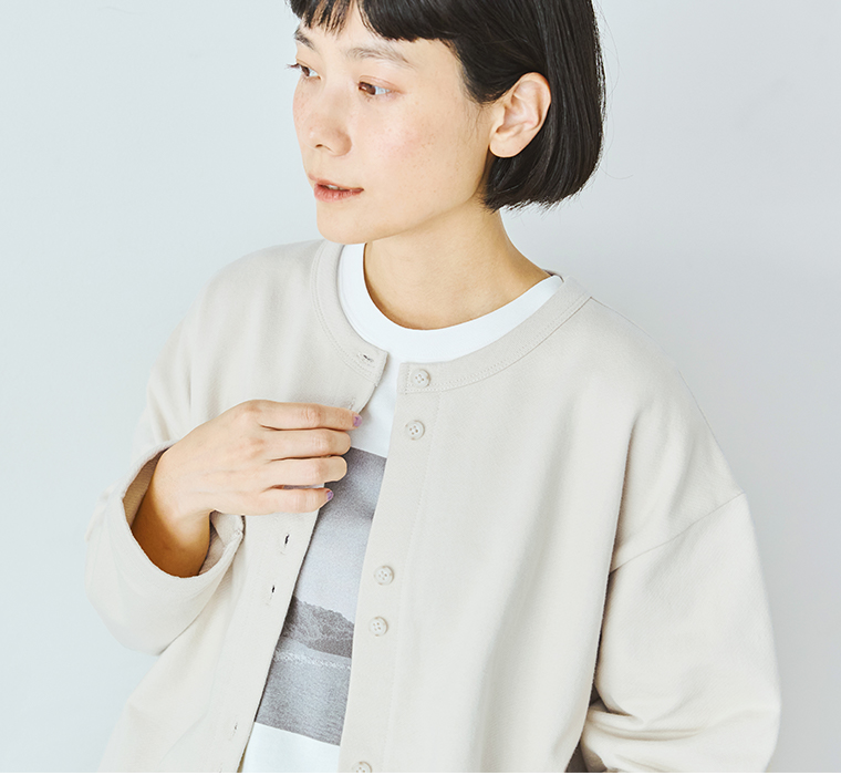 ナチュラルのカーディガンをボタンで留める手元のディテールカット