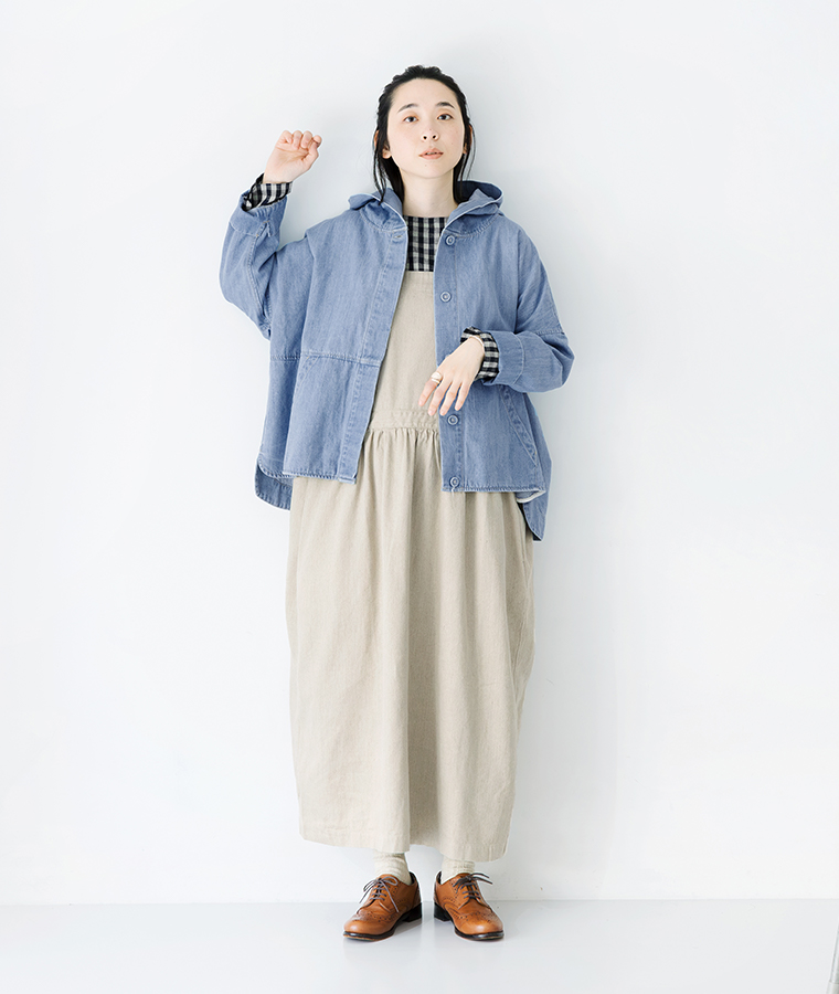 グレーのロングニットベストと白シャツ、白のパンツを合わせた全身コーディネート（黒ベレー帽と黒ブーツ）