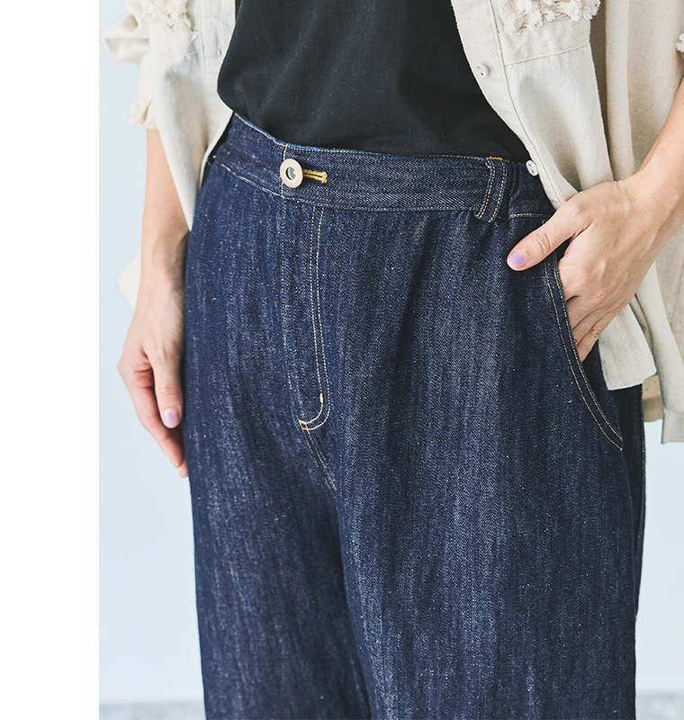 デニムパンツのウエストディテールとベージュステッチのアップ（白ボタン・サイドポケット付き）