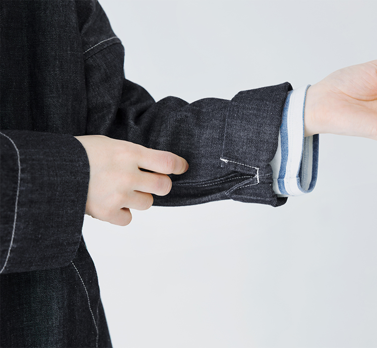 ダークデニムジャケットの袖を調整する手元のアップ