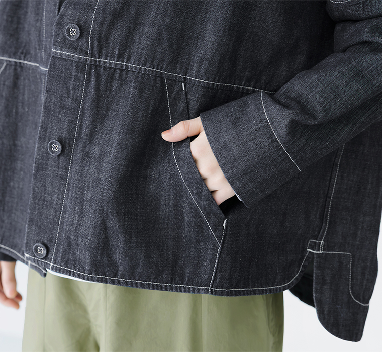 ダークデニムジャケットのサイドポケットに手を入れたディテールカット