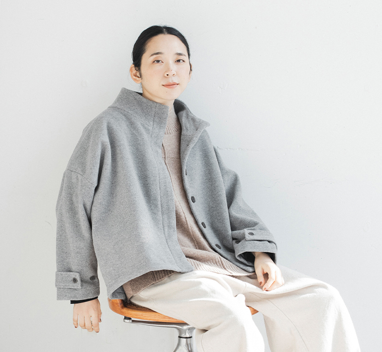 08Mabのスタンド襟ショートコートを着用した座りのコーディネートカット