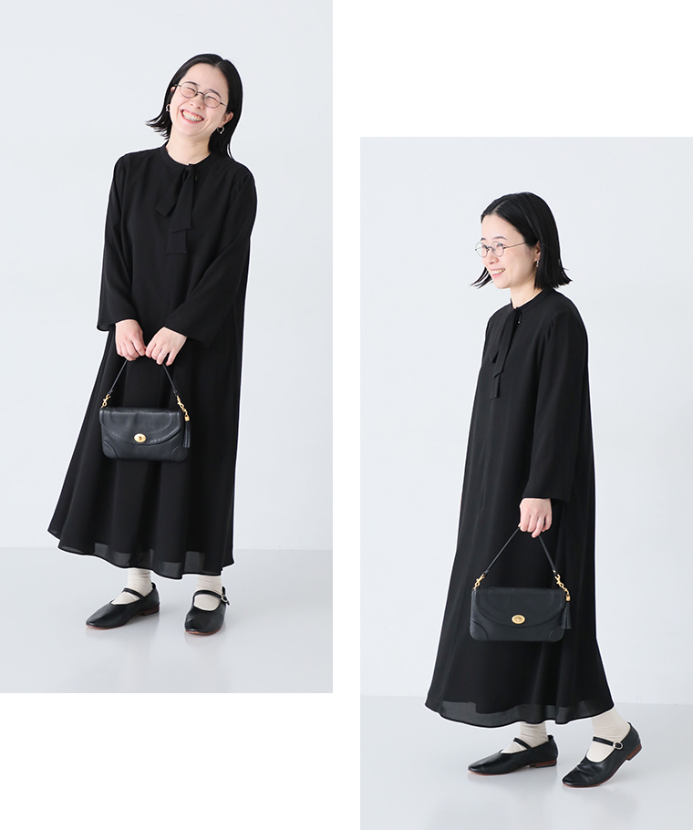 黒のボウタイ付きロングワンピースを着た女性の正面と横姿（白ソックスと黒のメリージェーンシューズ、黒のハンドバッグを合わせたコーディネート）