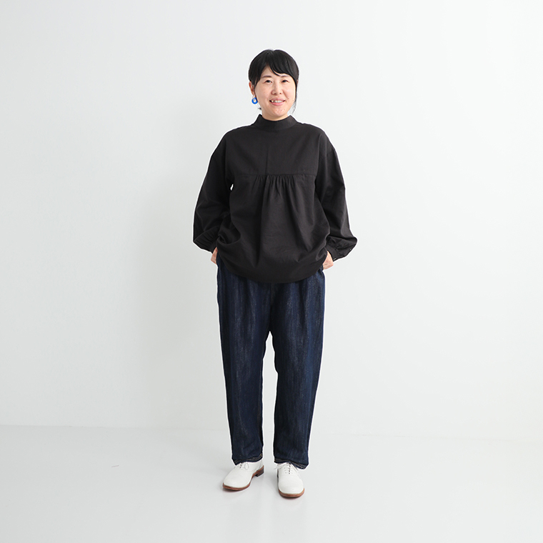 ブラックのギャザートップとデニムパンツを合わせたシンプルなカジュアルコーディネート（白のシューズ）