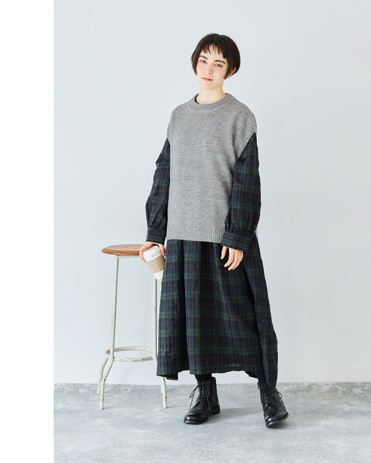グレーのニットとネイビー×グリーンのチェックワンピースを重ねた秋冬コーディネート（コーヒーカップを持つ女性）