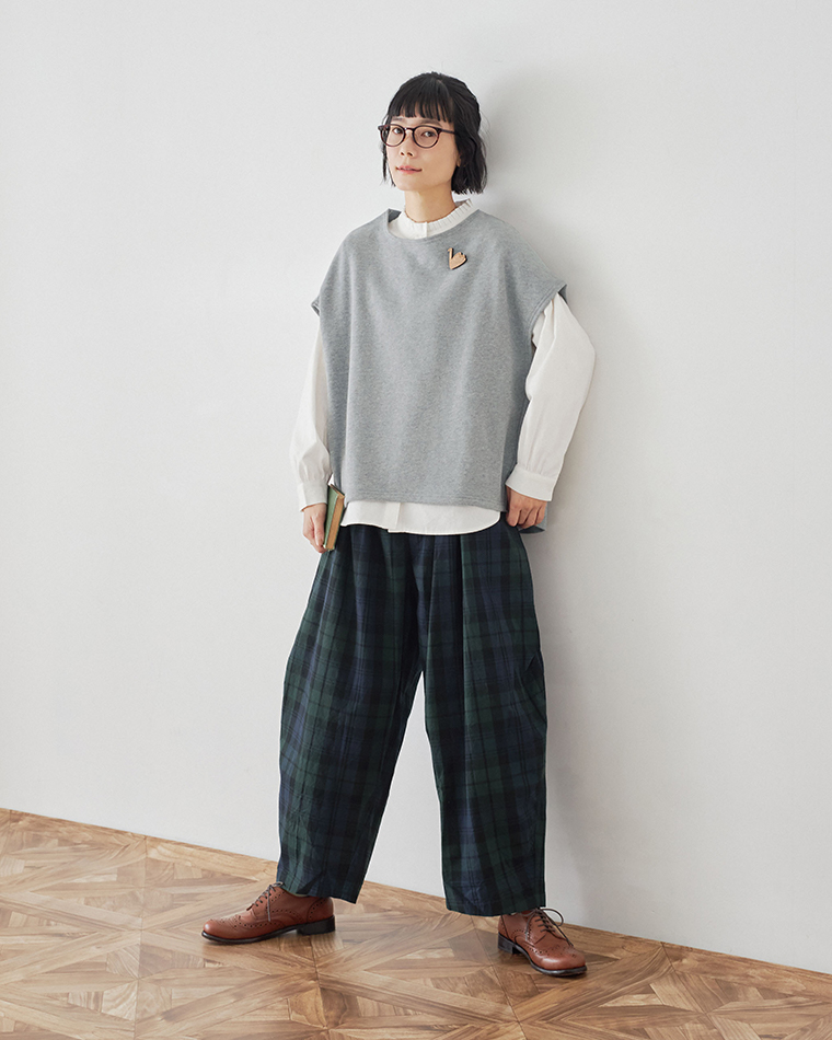 白のプリーツ襟ブラウスとグレーのベストを着た女性の表情カット（手を顔の横に添えたポーズ）