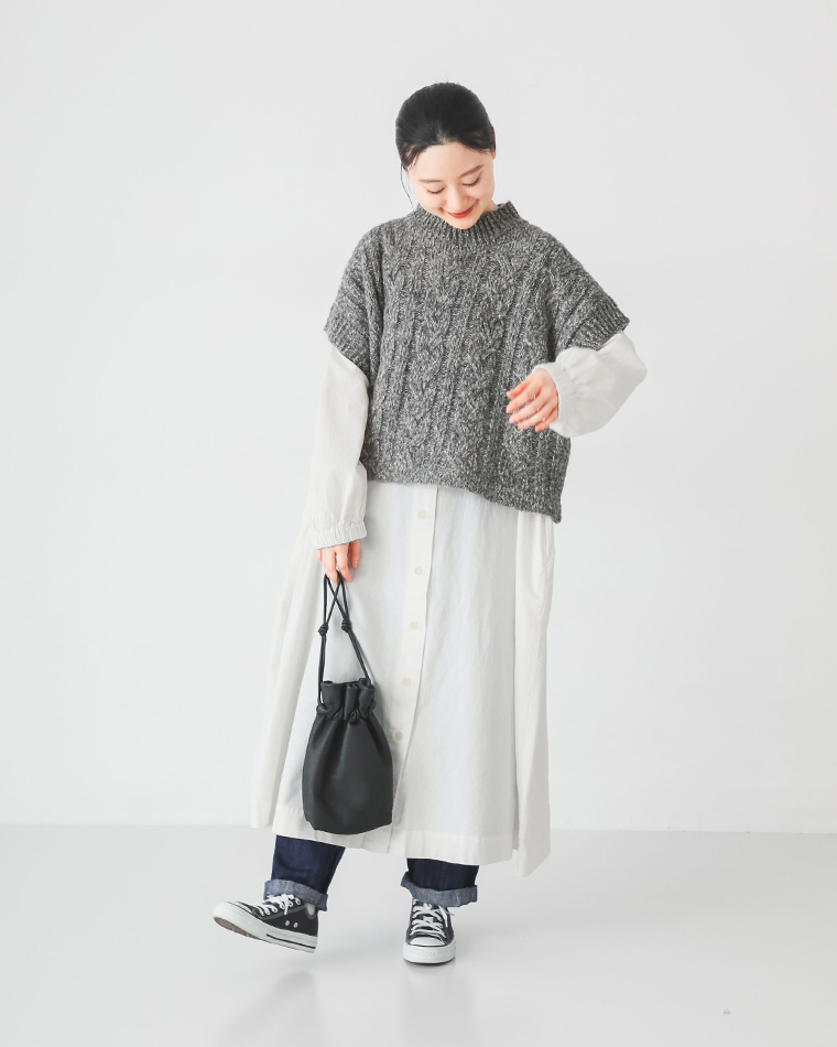 グレーの半袖ニットと白のロングシャツワンピースを重ねたカジュアルコーディネート（黒の巾着バッグを持つ女性）