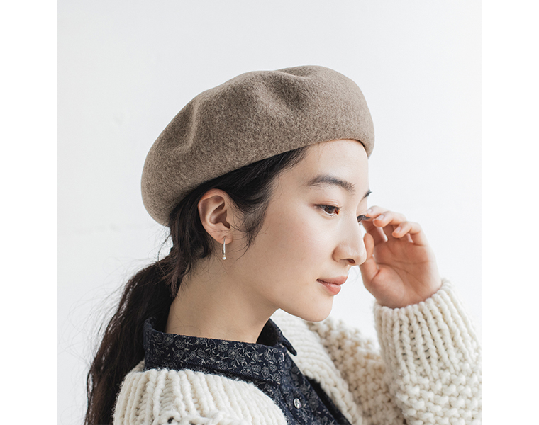 ベージュのバスクベレー帽を前浅めにかぶった女性の横顔。落ち着いた大人の雰囲気