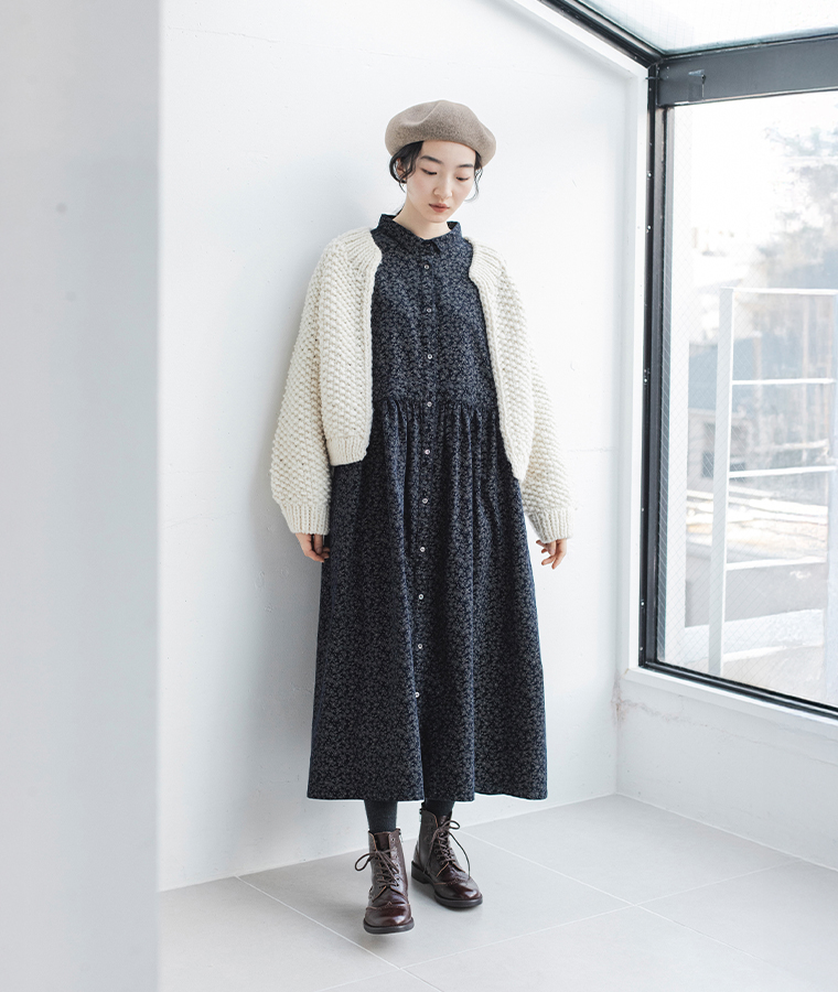 ベージュのバスクベレー帽を合わせた女性の全身コーデ。白ニットと黒ワンピースを重ねたナチュラルなスタイル