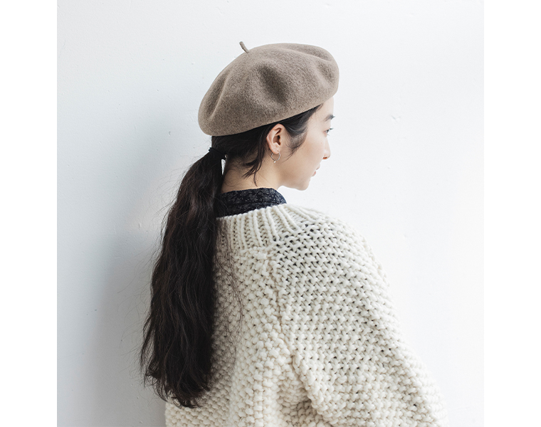 ベージュのバスクベレー帽を後ろ深めにかぶった女性の後ろ姿。ポニーテールの髪が見えるスタイル