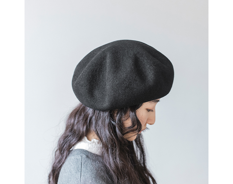 黒の八角ビッグベレー帽を角度をつけてかぶる女性の横顔。ふんわりとしたフォルムが分かる着用写真。