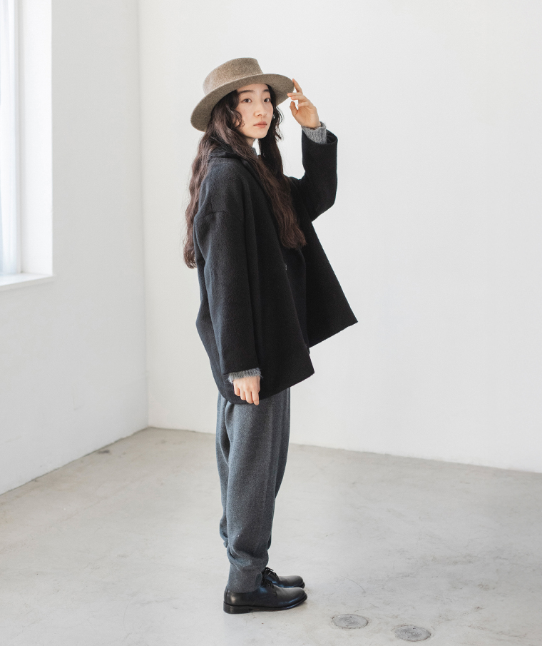 縮絨ウールのカンカン帽をかぶる女性が横向きに立っている姿