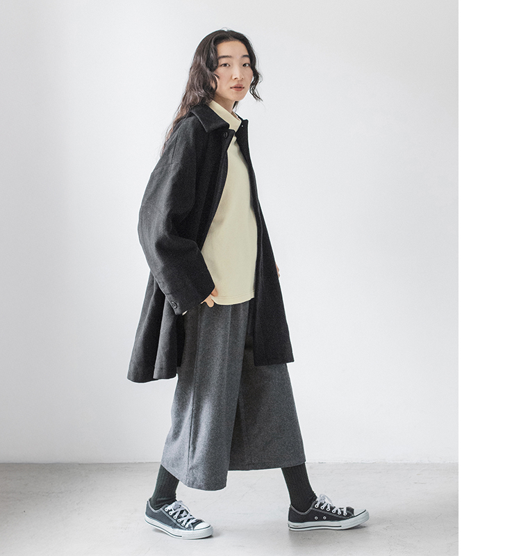 黒のコートとウールミックスガウチョパンツ（ダークグレー）を着た女性が横向きに歩いている