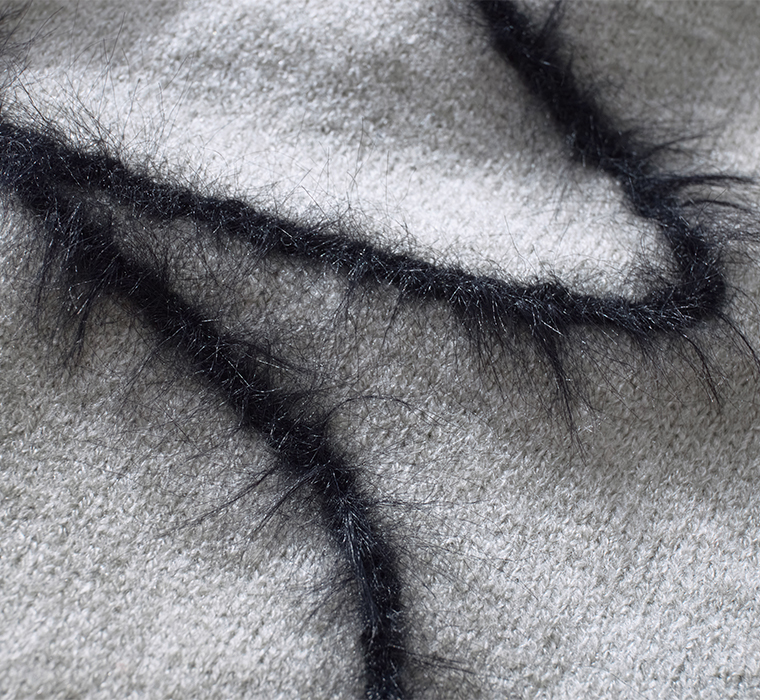 グレーの抽象ライン入りニットの生地アップ（黒のふわふわ素材のライン）