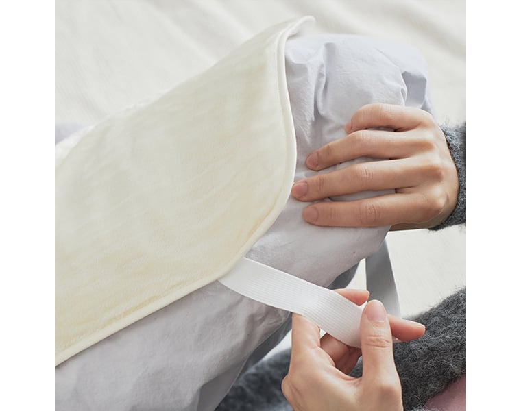 絹屋「【おやすみケア】思わず頬ずりしたくなるシルクの枕カバー」をゴムバンドで取り付ける手元のアップ