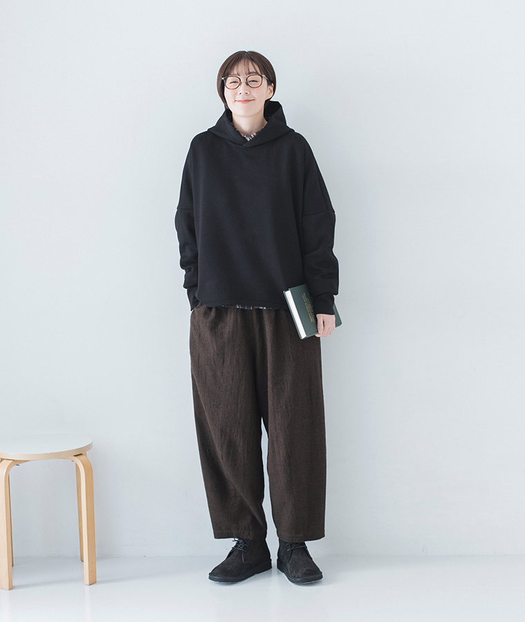 黒パーカー×ブラウンパンツの全身コーデ（立ち姿・本を手に）