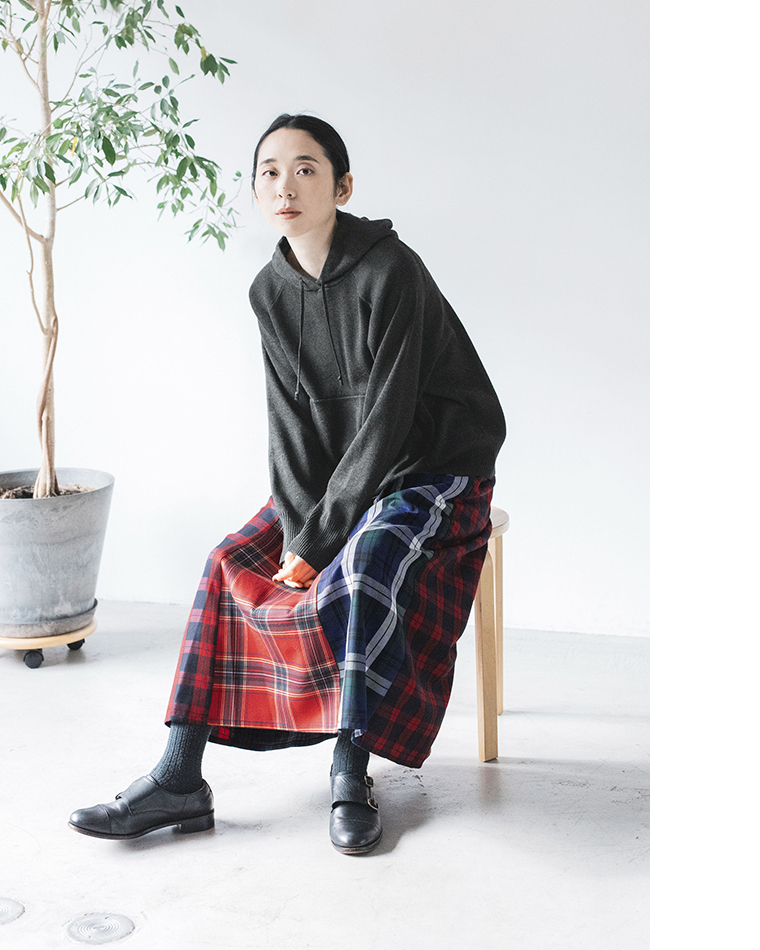ダークグレーのフーディーとチェック柄スカートのコーディネート（着席）