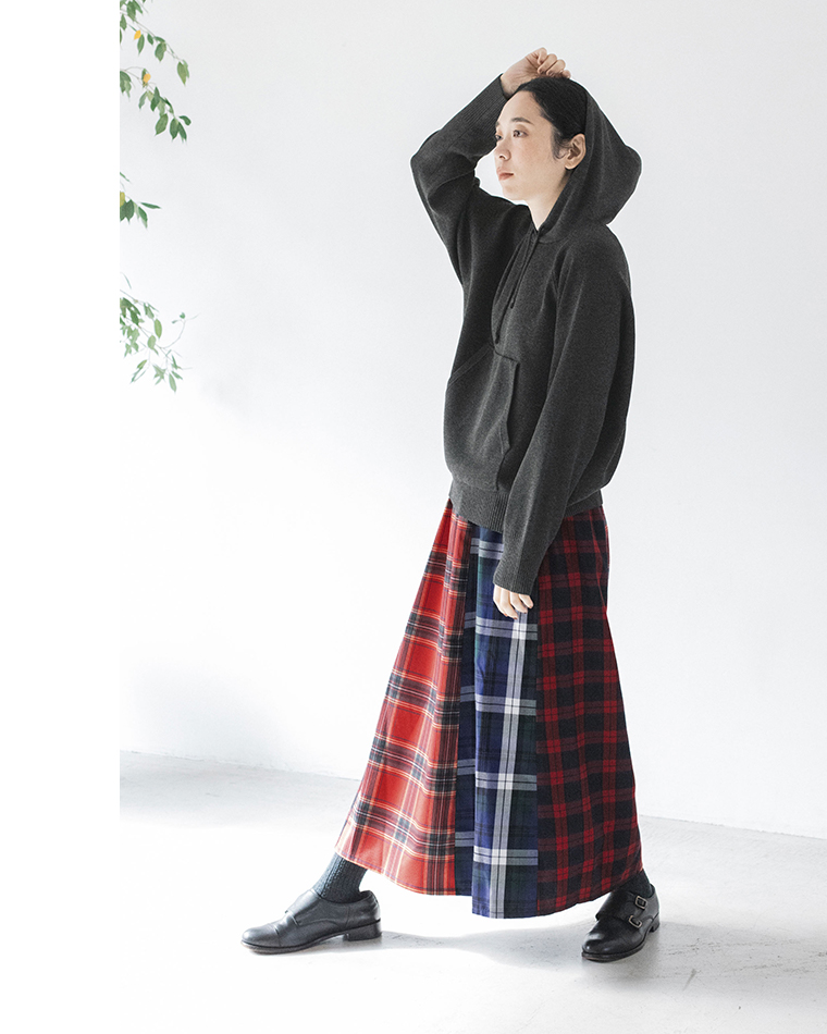 ダークグレーのフーディーとチェック柄スカートのコーディネート（フードをかぶった立ち姿）