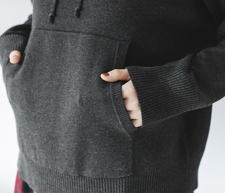 ダークグレーのフーディーの前ポケットに手を入れたディテール画像