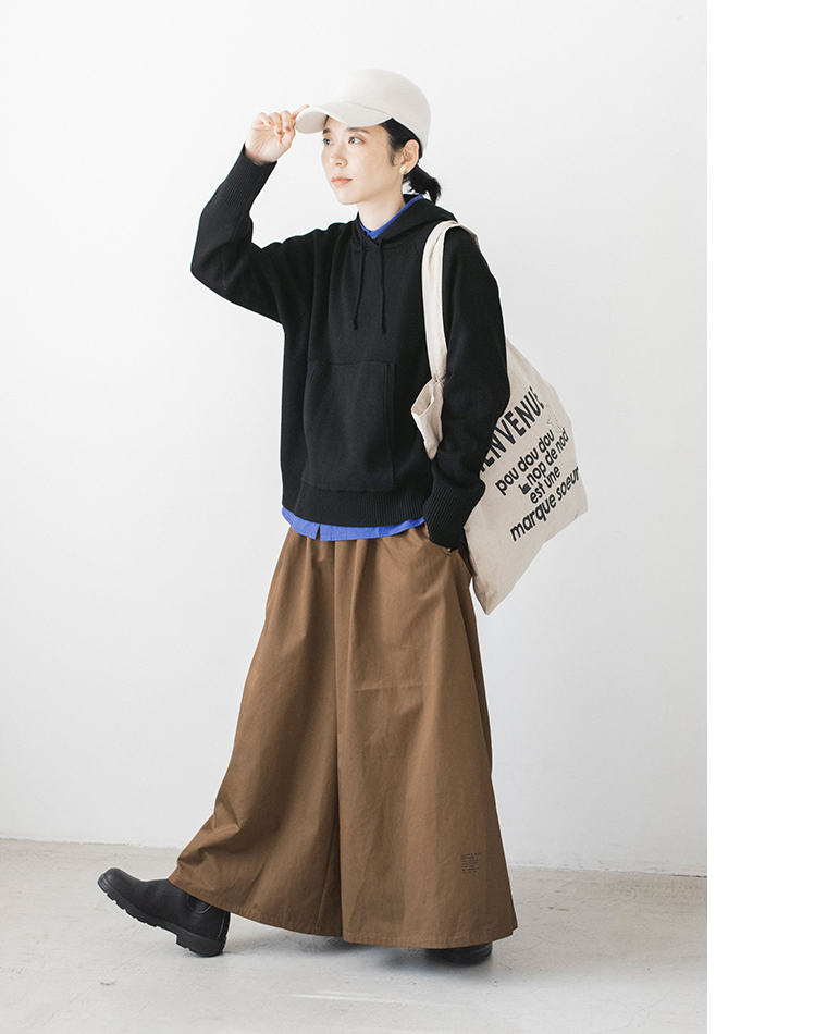 ブラックのフーディーとブラウンパンツのカジュアルコーディネート（帽子をかぶった立ち姿）