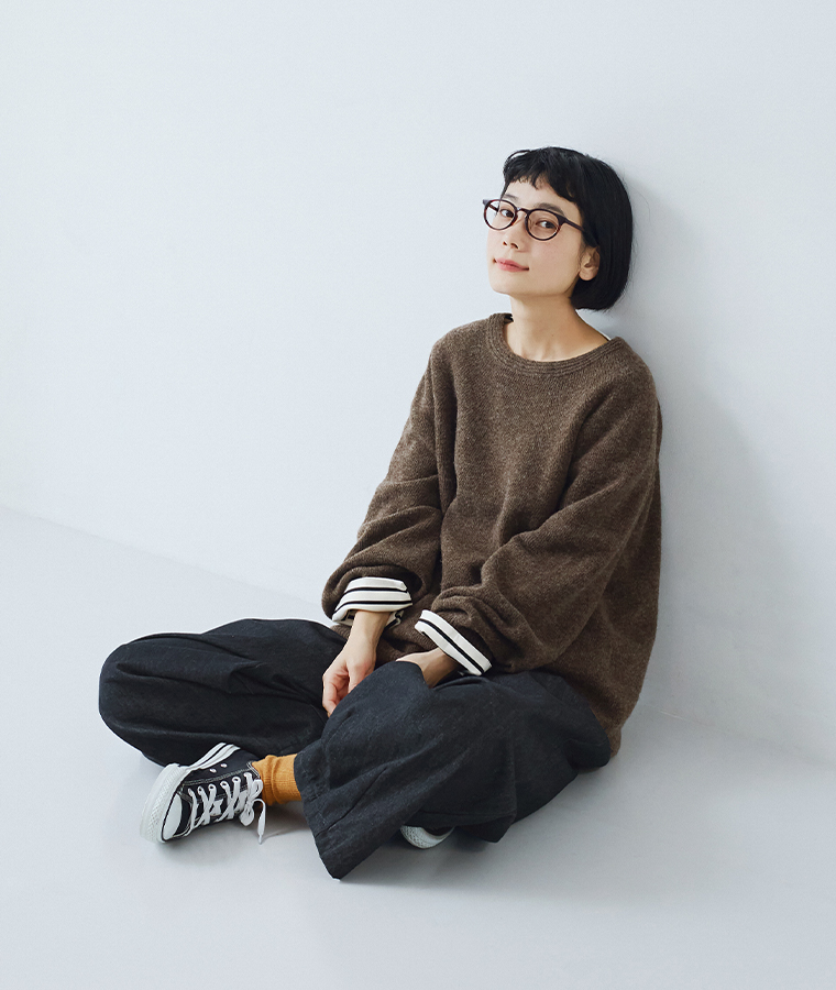 ホールガーメントプルオーバー（ブラウン）をパンツに合わせたカジュアルコーディネートの座ったスタイル