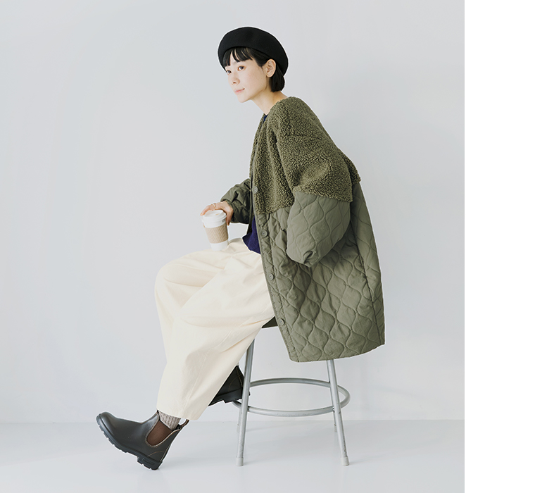 別注｜ボアキルトノーカラーコクーンコート（カーキ）を着てスツールに座る女性のコーディネート