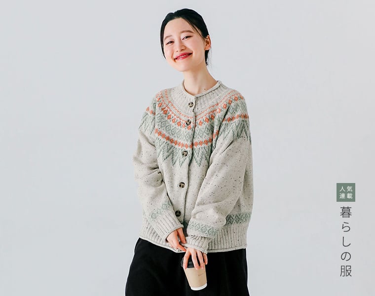 ネップペタル カーディガン（アイボリー）を着た女性がカップを手に微笑む上半身