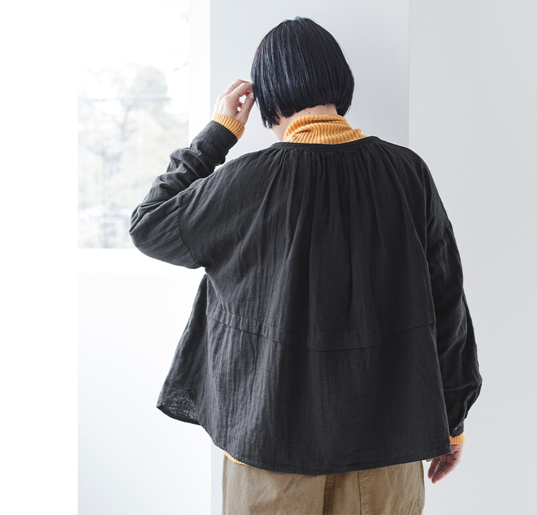 黒のトップスとマスタードのタートルネックを重ねた後ろ姿コーディネート