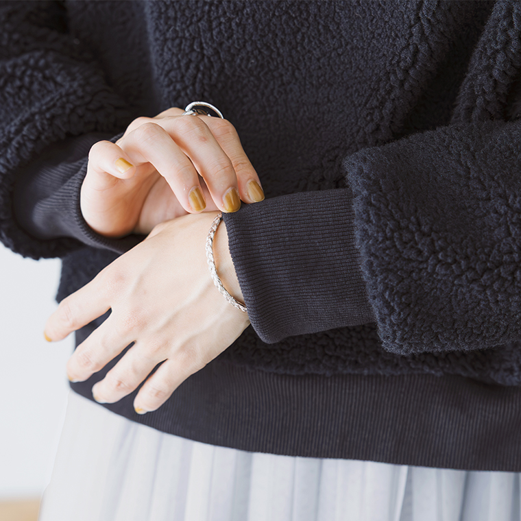 ネイビーのボアプルオーバーとシルバーアクセサリーの手元ディテール