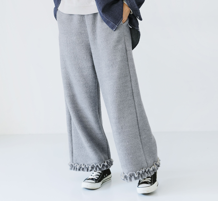 裾フリルデザインがアクセントのライトグレーのニットパンツを着用した冬のナチュラルコーディネート