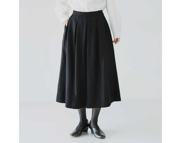 タック入りのフレアスカート。歩くたびに揺れる上品なシルエット。