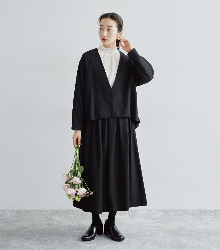 ノーカラージャケットとタックフレアスカートの横向きコーデ。裾ギャザーの後ろ姿がポイント。