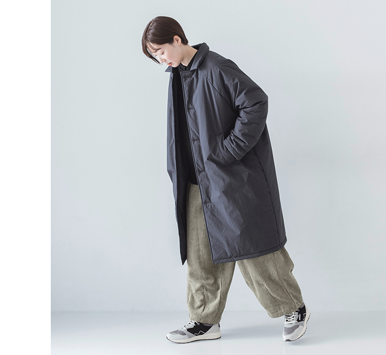 コットンナイロン中綿コクーンコート ネイビーを着用したモデルの前かがみの全身