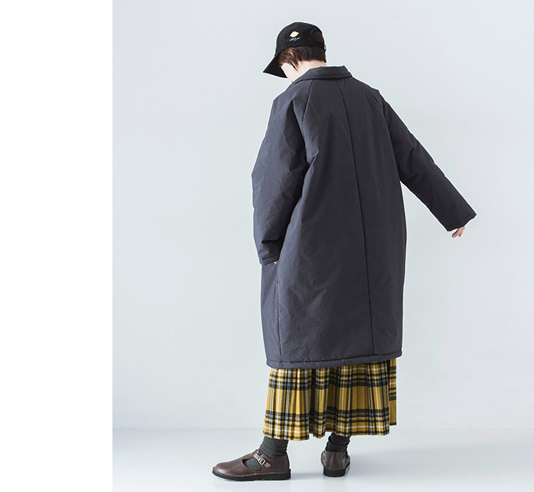 イエローチェックスカートとコットンナイロン中綿コクーンコート ネイビーを着用したモデルの全身後ろ姿