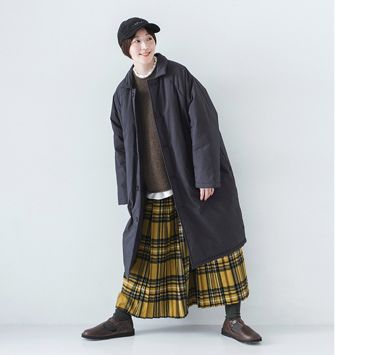 イエローチェックスカートとコットンナイロン中綿コクーンコート ネイビーを着用したモデルの全身斜め正面