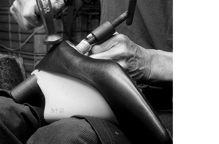 靴型にレザーを固定し、金槌で仕上げる職人の手元