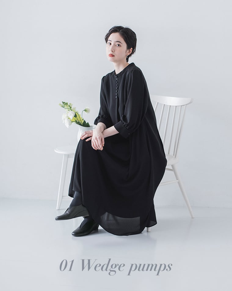 DOUBLETREEのブラックウェッジソールパンプスを着用したコーディネート（黒のロングワンピースと白背景）