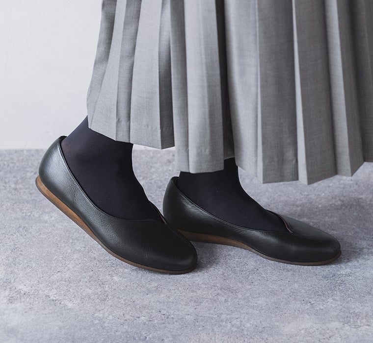 グレーのセットアップとと黒タイツに合わせたDOUBLETREEアシンメトリーシームパンプスの足元アップ