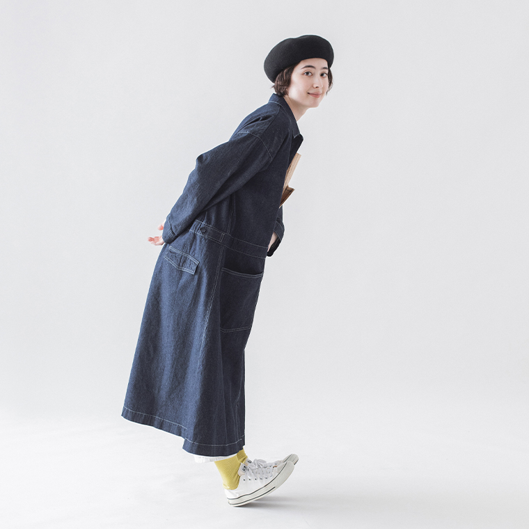 重ね着コーデでデニムコートワンピースを着用した女性モデルの横向き全身スタイル