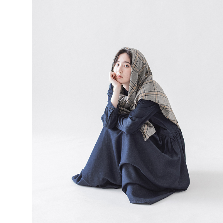 チェックストールを羽織って座る女性モデルとデニムワンピースのコーディネート