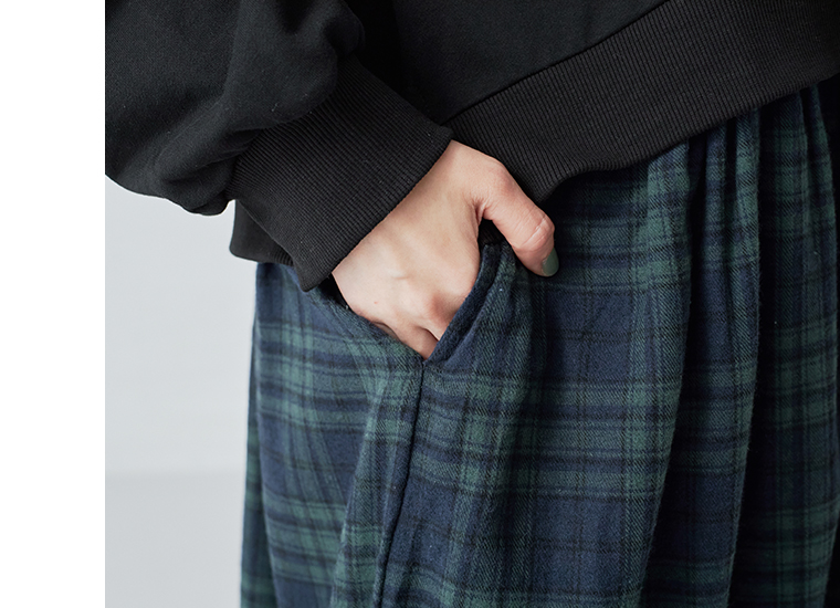 ブラックウォッチ柄スカート部分のポケットに手を入れたディテール写真。生地の風合いとギャザー感が分かるアップ画像。