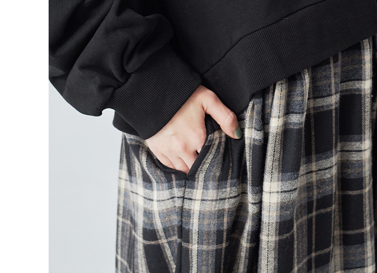 ブラックチェック柄スカート部分のポケットに手を入れたディテール写真。生地の風合いやギャザー感が分かるアップ画像。