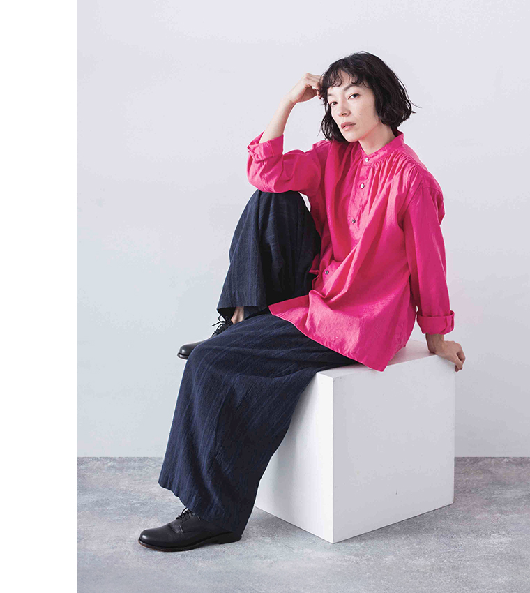 ピンクのシャツをネイビーのスカートに合わせて座ったコーディネート