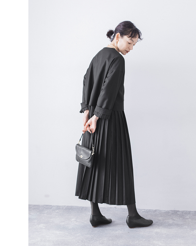 ブラックのジャケットとワンピースの後ろ姿（バッグを背中に持ったスタイル）