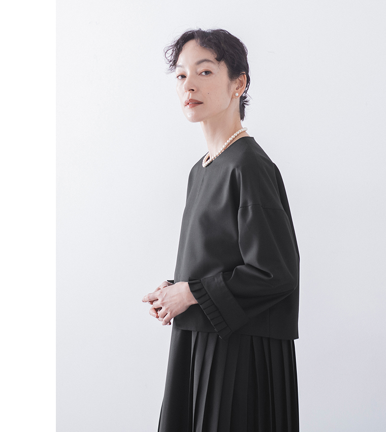 ブラックのジャケットの上半身アップ横姿（パールネックレスとイヤリングのアクセント）