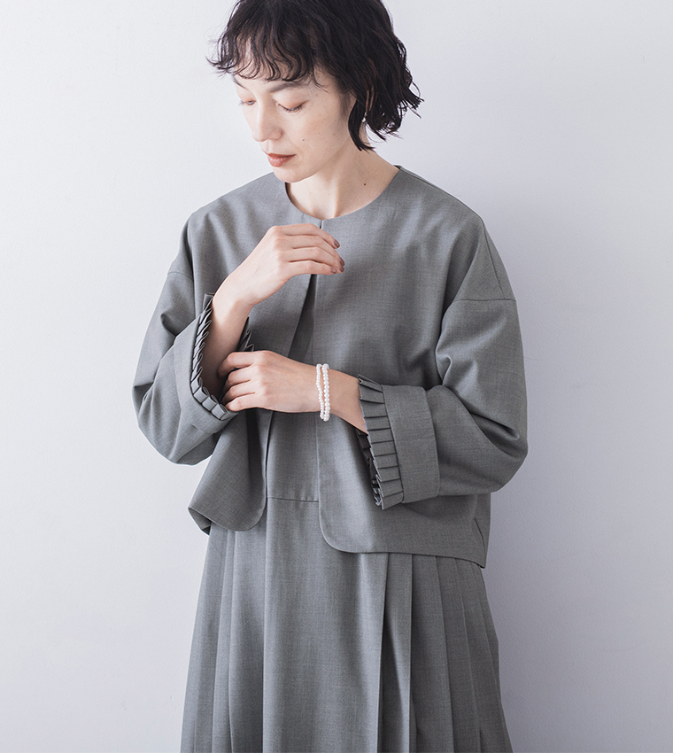 グレージャケットの袖口プリーツと白いブレスレットのディテール