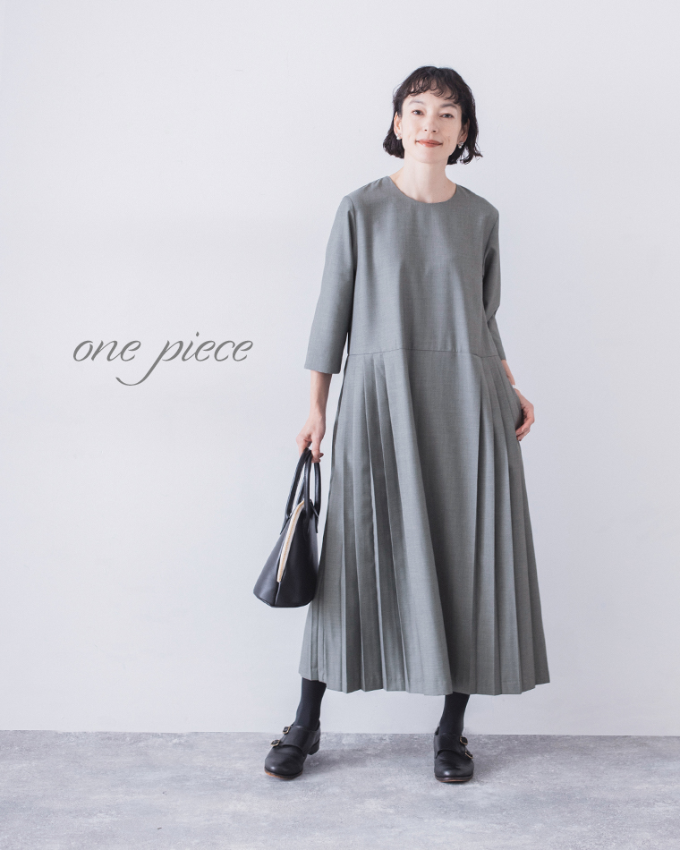 グレーのプリーツワンピースを着用した正面スタイル（黒のバッグとローファー付き）