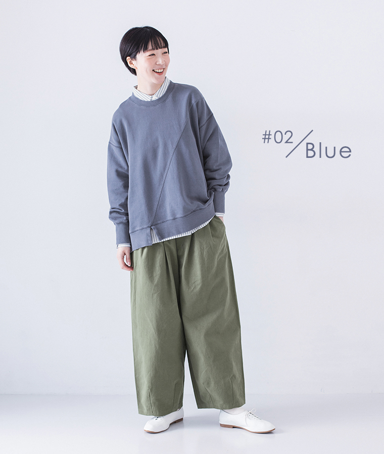 ピグメント裏毛斜め切り替えプルオーバー ブルーを着用したモデルの全身斜め向きでカーキのワイドパンツと白のレースアップシューズを合わせたコーディネート