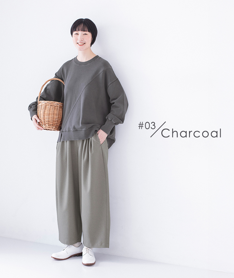 ピグメント裏毛斜め切り替えプルオーバー チャコールを着用したモデルの全身正面でかごバッグを持ちワイドパンツと白のレースアップシューズを合わせたコーディネート