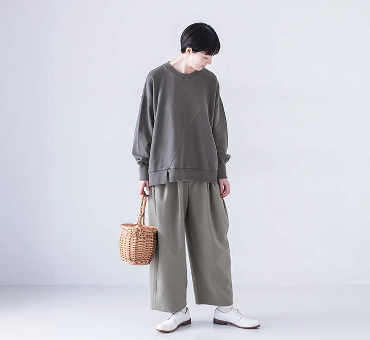 ピグメント裏毛斜め切り替えプルオーバー チャコールを着用したモデルの全身正面で同系色のワイドパンツと白のレースアップシューズを合わせたコーディネート